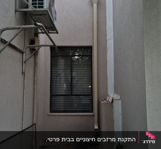 צינור ניקוז על קיר חיצוני ליד חלון